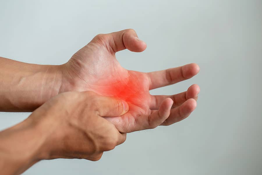 A close-up of a hand showing signs of trigger finger, with one finger being pressed and attention drawn to the palm. Early Signs of Trigger Finger You Should Not Ignore - Spire Orthopaedic Centre